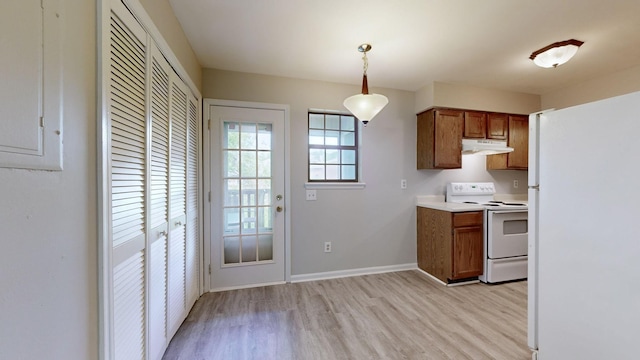 kitchen featuring pendant lighting, white appliances, and light hardwood / wood-style flooring