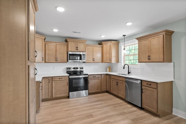 kitchen with tasteful backsplash, sink, stainless steel appliances, and light hardwood / wood-style flooring