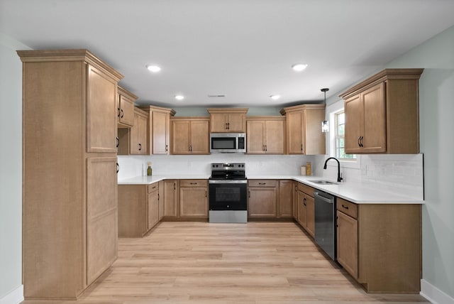 kitchen featuring sink, stainless steel appliances, light hardwood / wood-style flooring, pendant lighting, and decorative backsplash