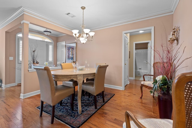 dining room with light hardwood / wood-style flooring, crown molding, and a notable chandelier