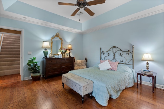 bedroom with a raised ceiling, ceiling fan, and hardwood / wood-style flooring