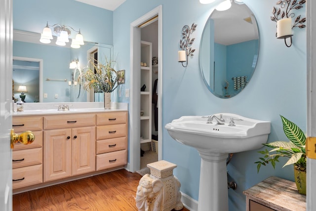 bathroom with built in shelves, dual sinks, and wood-type flooring