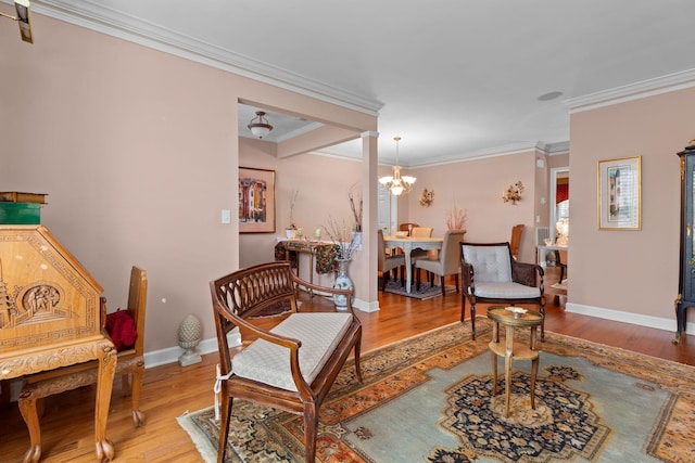 sitting room with hardwood / wood-style flooring, ornate columns, ornamental molding, and a chandelier