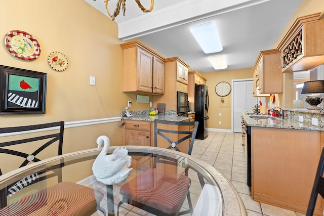 kitchen featuring sink, light stone counters, light brown cabinetry, light tile patterned floors, and black appliances