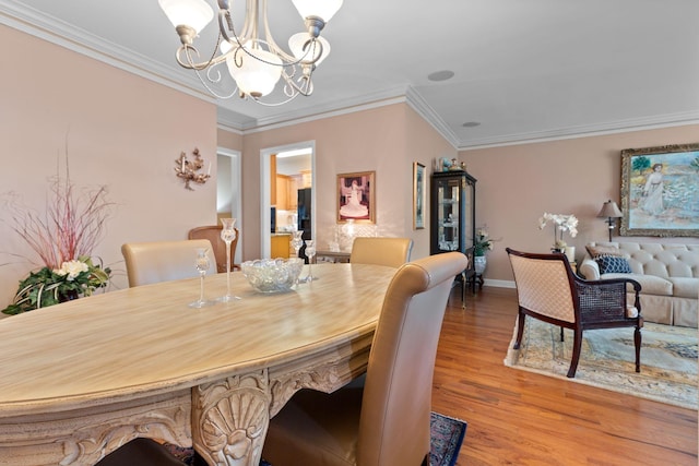 dining space featuring light wood-type flooring, crown molding, and a chandelier