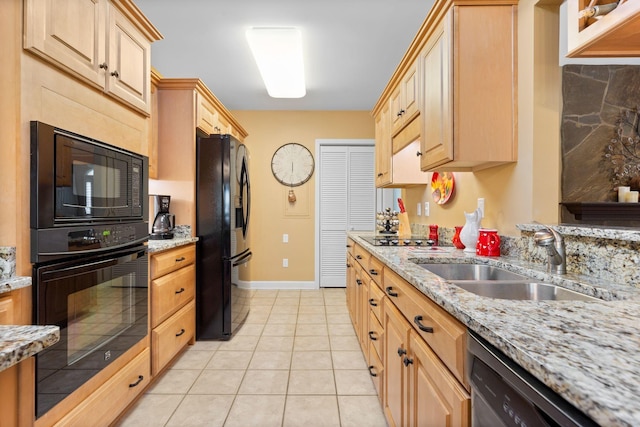 kitchen featuring sink, light stone counters, light brown cabinetry, light tile patterned flooring, and black appliances