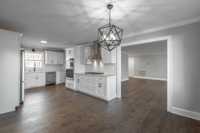 kitchen featuring wall chimney exhaust hood, hanging light fixtures, stainless steel appliances, tasteful backsplash, and white cabinets