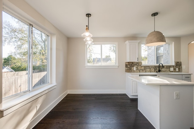 kitchen featuring sink, white cabinetry, tasteful backsplash, dark hardwood / wood-style flooring, and pendant lighting