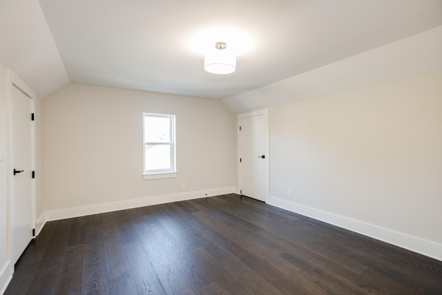 unfurnished room with lofted ceiling and dark wood-type flooring