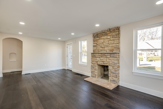 unfurnished living room with a stone fireplace and dark hardwood / wood-style floors