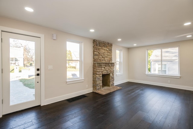 unfurnished living room with dark hardwood / wood-style floors and a stone fireplace