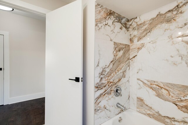 bathroom with hardwood / wood-style flooring and tiled shower / bath combo