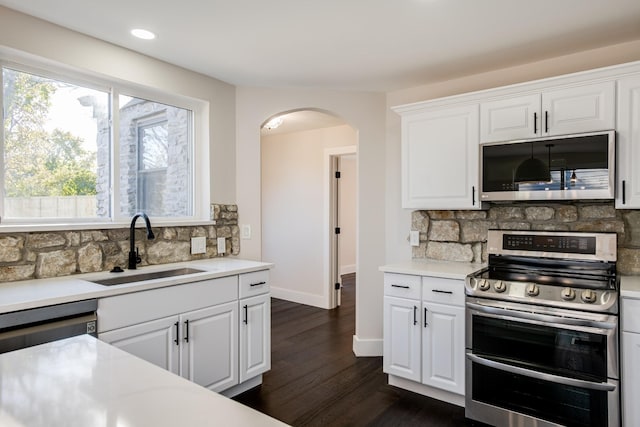 kitchen with dark wood-type flooring, sink, tasteful backsplash, appliances with stainless steel finishes, and white cabinets