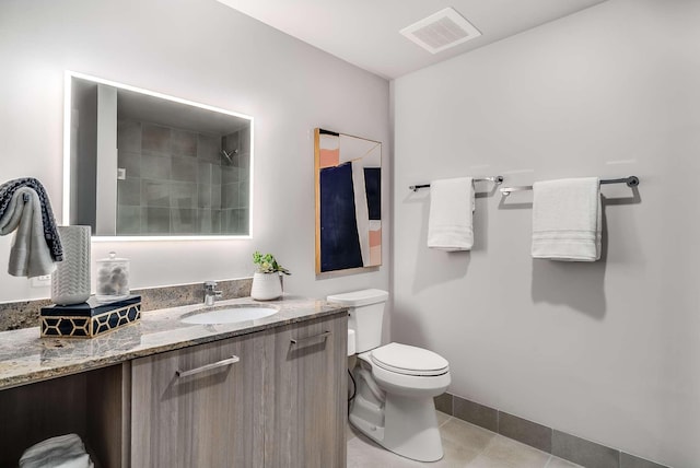 bathroom with tile patterned floors, walk in shower, vanity, and toilet