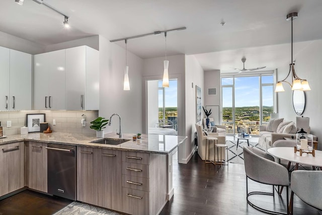 kitchen with pendant lighting, light stone counters, white cabinetry, and sink