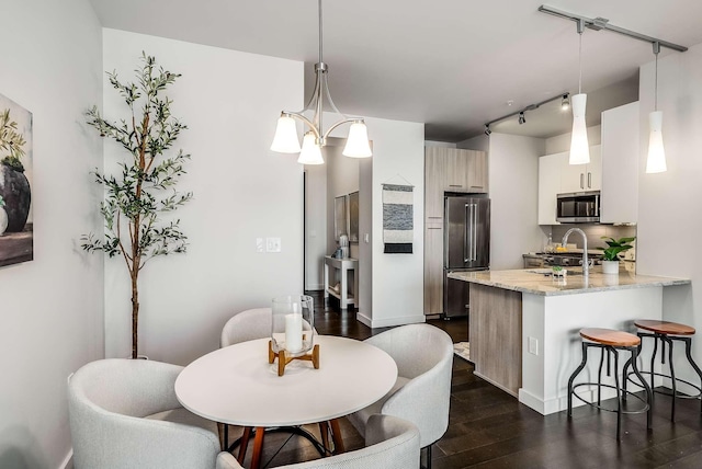 kitchen featuring light stone countertops, rail lighting, stainless steel appliances, tasteful backsplash, and decorative light fixtures