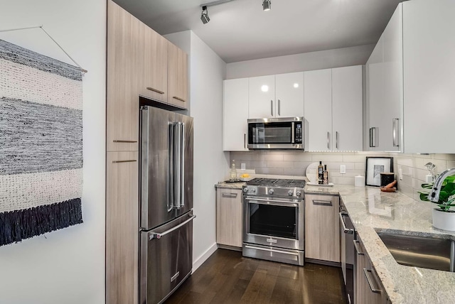 kitchen featuring sink, light brown cabinets, light stone counters, white cabinets, and appliances with stainless steel finishes