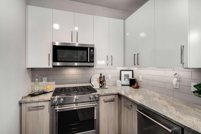 kitchen with white cabinets, light stone counters, and appliances with stainless steel finishes