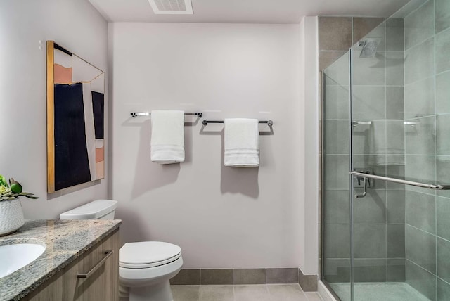 bathroom featuring tile patterned floors, vanity, a shower with shower door, and toilet