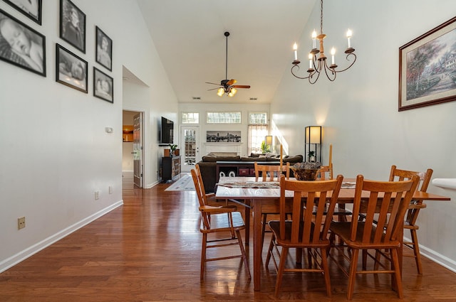 dining space with dark hardwood / wood-style floors, ceiling fan with notable chandelier, and high vaulted ceiling