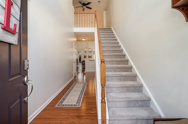 interior space with ceiling fan, a towering ceiling, and wood-type flooring