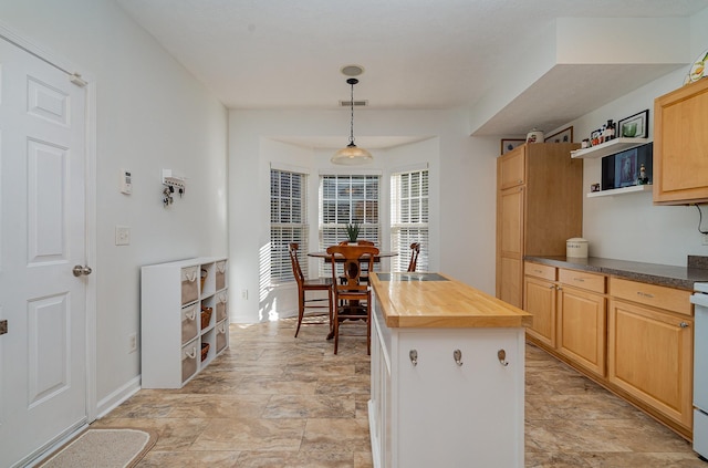 kitchen featuring wood counters, sink, light brown cabinets, a center island, and hanging light fixtures