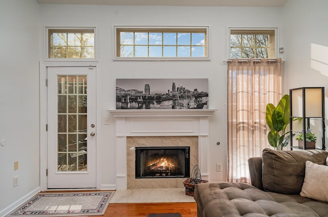 living room featuring hardwood / wood-style flooring, a premium fireplace, and a high ceiling