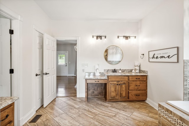 bathroom featuring vanity and a relaxing tiled tub