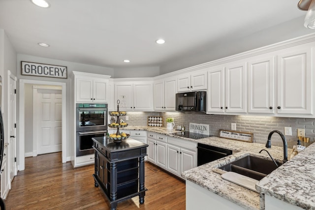 kitchen featuring a center island, black appliances, white cabinets, sink, and light stone countertops