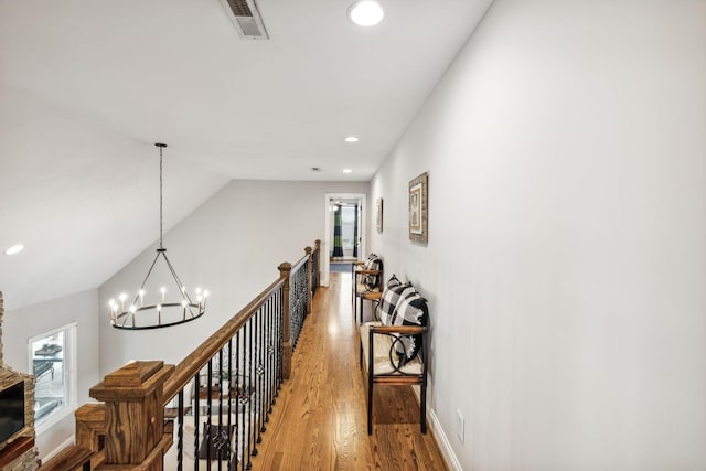 hall featuring a notable chandelier, wood-type flooring, a wealth of natural light, and vaulted ceiling