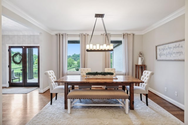 dining area featuring a healthy amount of sunlight, wood-type flooring, crown molding, and french doors