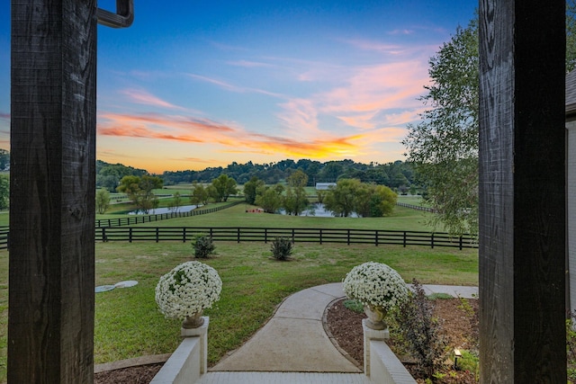 yard at dusk with a water view and a rural view