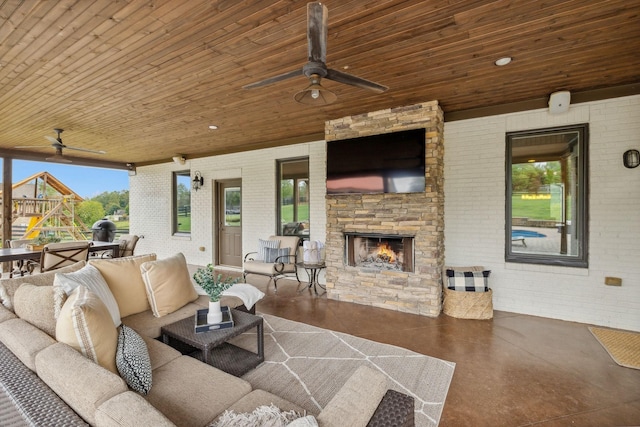 living room with an outdoor stone fireplace, wooden ceiling, and brick wall