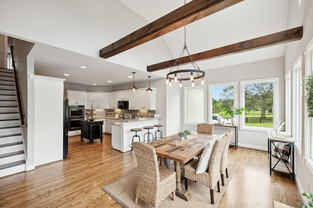 dining area with a chandelier, vaulted ceiling with beams, and light hardwood / wood-style flooring