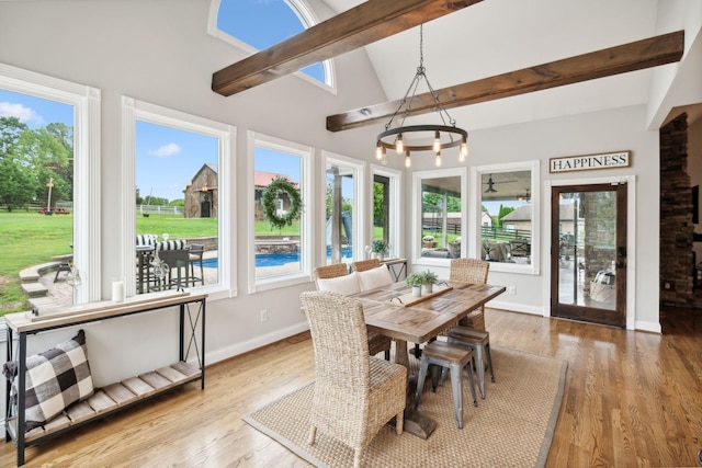 sunroom with lofted ceiling with beams, a healthy amount of sunlight, and an inviting chandelier