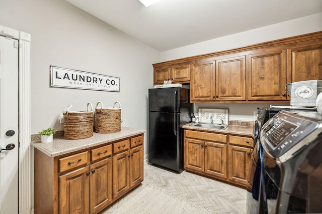 kitchen featuring stove, light parquet flooring, black fridge, and sink