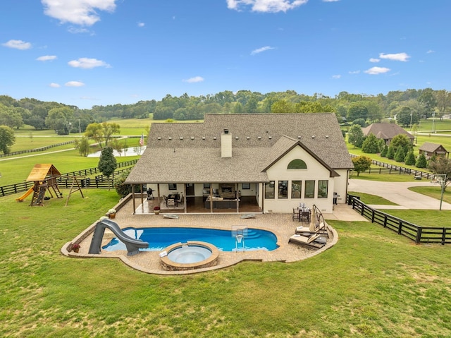 view of pool featuring a lawn, a rural view, a patio area, and an in ground hot tub