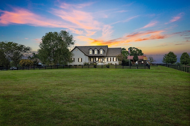 back house at dusk with a rural view and a yard