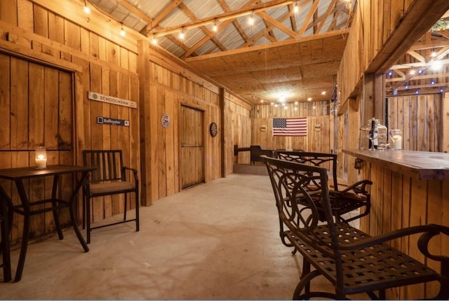 interior space featuring beam ceiling, high vaulted ceiling, bar area, wood walls, and wood ceiling