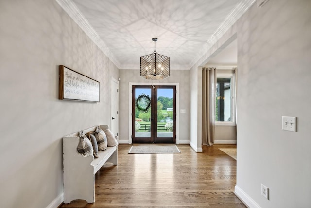 foyer entrance featuring a chandelier, french doors, ornamental molding, and wood-type flooring