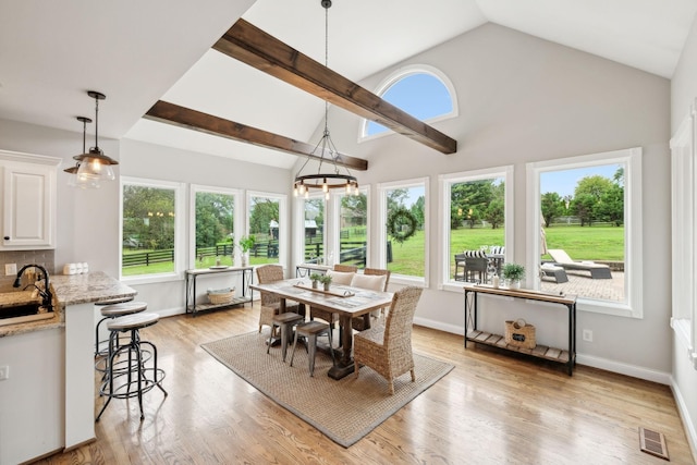 sunroom featuring an inviting chandelier, vaulted ceiling, and sink