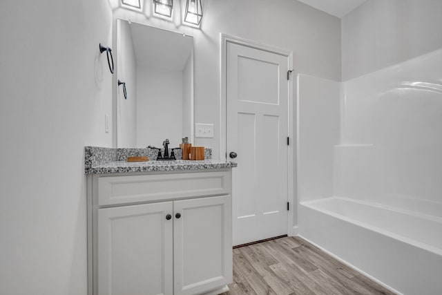 bathroom with bathtub / shower combination, vanity, and hardwood / wood-style flooring