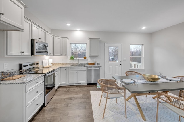 kitchen featuring white cabinets, appliances with stainless steel finishes, light hardwood / wood-style flooring, and sink