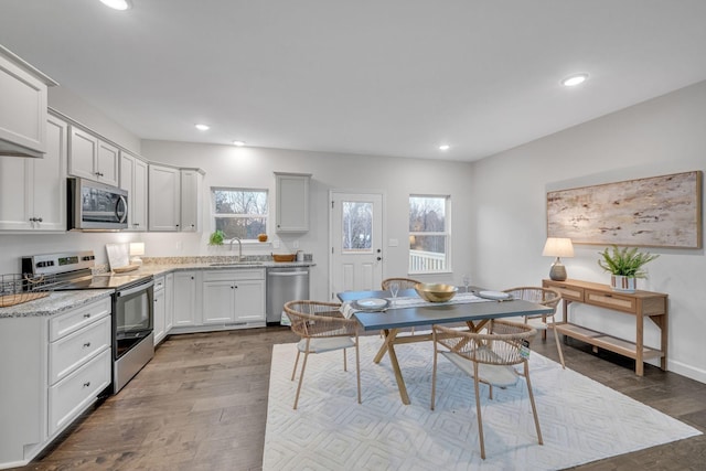 kitchen featuring dark wood-type flooring, white cabinets, sink, appliances with stainless steel finishes, and light stone counters