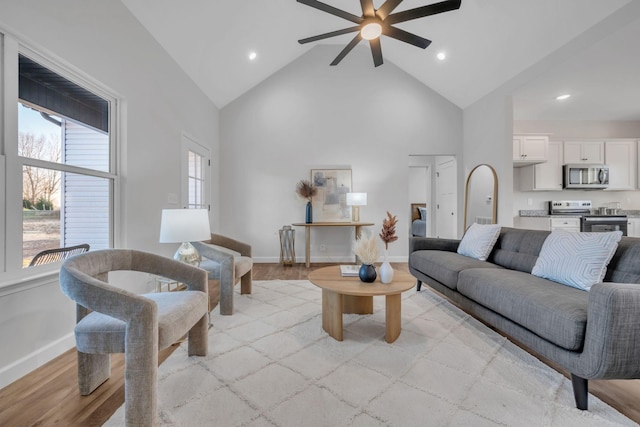 living room with light hardwood / wood-style floors, high vaulted ceiling, and ceiling fan