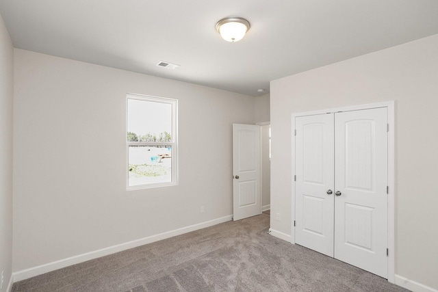 unfurnished bedroom featuring light carpet and a closet