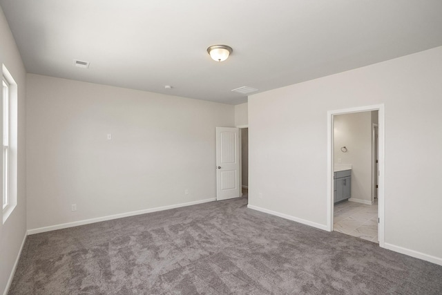 unfurnished bedroom featuring connected bathroom and light carpet