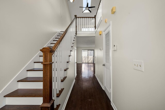 stairs featuring a towering ceiling, ceiling fan, and hardwood / wood-style flooring