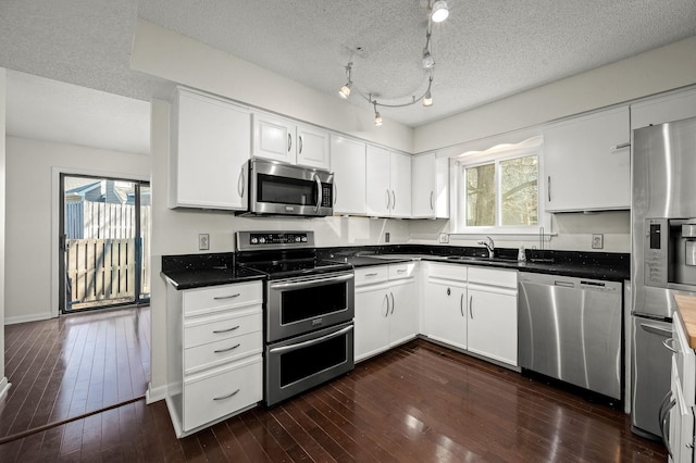 kitchen featuring stainless steel appliances, sink, dark wood-type flooring, and white cabinets