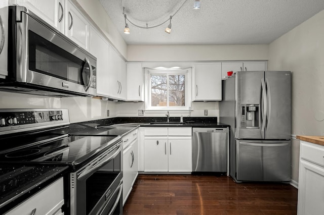 kitchen with sink, white cabinetry, a textured ceiling, track lighting, and appliances with stainless steel finishes